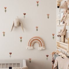 a baby's room with pink flowers and wall decals, including a rainbow