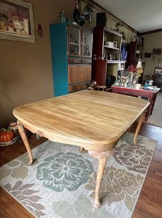 a wooden table sitting on top of a rug in a living room next to a blue door