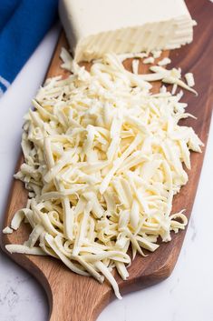 a wooden cutting board topped with cheese next to a block of butter and a blue towel