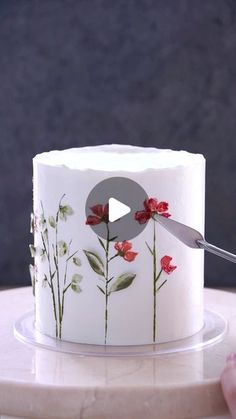 a white cake with red flowers on it and a knife sticking out of the top