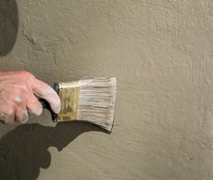 a person holding a paint brush on top of a wall