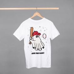 a t - shirt hanging on a clothes rack with a baseball bat and ball in it