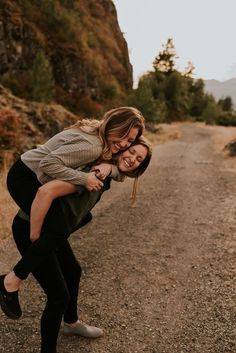 two women are hugging on the side of a dirt road