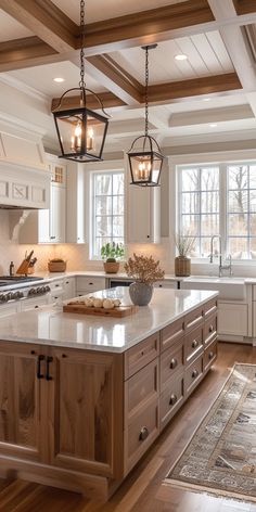 a large kitchen with an island in the middle and two hanging lights over it's windows