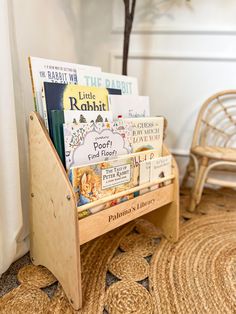 there is a wooden book stand with books in it on the floor next to a wicker chair