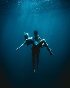 two people floating in the water with their arms around each other