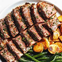 steak, green beans and potatoes on a white plate with parsley garnish