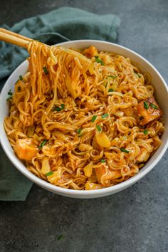 a white bowl filled with noodles and chopsticks on top of a blue towel