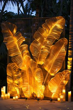 some candles are lit up in the shape of a plant with leaves on it and surrounded by palm trees