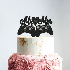 a cake with two video game controllers on top and pink frosting flowers in the middle