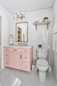 a white and pink bathroom with hexagonal floor tiles on the walls, gold accents