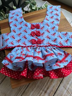 a blue dress with red and white polka dots on it, sitting on a wooden table