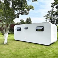 a large white building sitting on top of a lush green field next to a tree