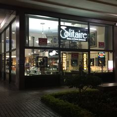 a store front at night with its lights on and the sign lit up for business