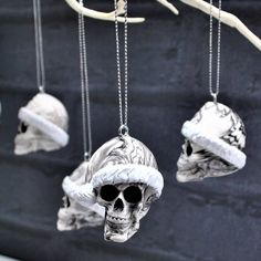 three skulls wearing hats hanging from chains