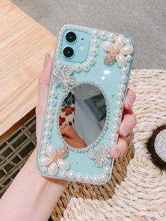 a person holding a phone case with pearls on it