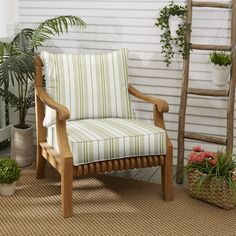 a wooden chair sitting on top of a rug next to a potted plant and ladder