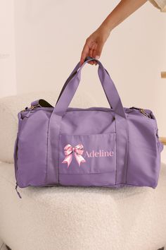 Elevate your everyday style with our Personalized Name Duffel Bag, a versatile accessory that seamlessly blends fashion and functionality. This 9-inch tall, 18.5-inch long, and 10.5-inch wide bag is designed to add a touch of sophistication to your daily outings. What sets our duffle bag apart is its unique design. The compartments are separated from each other with zippers from both the top and the side of the bag. A variety of color choices with many different font options are available for yo Functional Purple Bag For Daily Use, Functional Purple Shoulder Bag, Sporty Travel Bag For School, Sporty Purple Gym Bag For Travel, Purple Duffle Bag For Daily Use, Functional Purple Bag With Adjustable Strap, Sporty School Travel Bag With Adjustable Strap, Functional Purple Gym Bag For Daily Use, Functional Purple Shoulder Bag For School