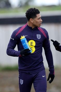 a soccer player wearing gloves and holding a water bottle