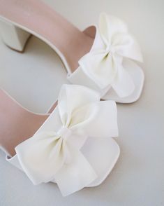 two pairs of white shoes with bows on them