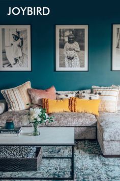 a living room with blue walls and pictures on the wall above the couches,