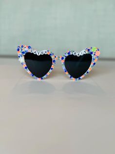 Bedazzled retro heart sunglasses perfect for any University of Florida fan.  Use these sunglasses to complete your Game Day outfit or gift to any Florida Gator! Please note this is a made to order item and no two sunglasses will be the same.  Exact color and placement of gems will have slight variation. Ensuring your purchases arrive in perfect condition is important to me! Sunglasses are packaged in hard, sturdy boxes with crinkle cut packing paper. All sunnies are shipped with a squeeze top soft leather case and cleaning cloth. I am happy to provide custom orders! Please message me if you would like different color rhinestones, sunglasses, color of letters, or word combo than displayed.  I am happy to answer any questions. Returns or exchanges are not accepted due to the custom nature of Retro Sunglasses With Tinted Lenses As Gift, Retro Sunglasses With Tinted Lenses For Gift, Retro Sunglasses With Tinted Lenses As A Gift, Heart-shaped Glass Sunglasses For Gift, Heart-shaped Glass Sunglasses As Gift, Heart-shaped Sunglasses For Valentine's Day Gift, Heart-shaped Sunglasses With Uv Protection As Gift, Cute Glass Sunglasses For Gift, Cute Glass Sunglasses As Gift