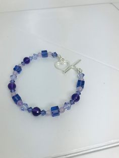 If you love shades of purple, this bracelet is for you. The bracelet made of Amethyst Beads, Swarovski Tanzanite Crystals and Lavender Jade beads is absolutely lovely.  The heart link is the perfect finish.   2 - 6 mm Genuine Faceted Amethyst Round Beads  2 - 6 mm Genuine Smooth Amethyst Round Beads  5 - 6 mm Swarovski Tanzanite Square Beads  6 - 6 mm Tanzanite Bicone Beads  8 - 4 mm Swarovski Tanzanite Bicone Beads 10 - 4 mm Lavender Jade Round Beads    1 - 15 mm Sterling Silver Heart Link Total Length - 7 1/2 inches The bracelet will arrive in a silky zippered jewelry bag (color may vary). Lavender Bracelets With Spacer Beads As Gift, Lavender Bracelets With Spacer Beads For Gift, Purple Heart Beaded Bracelets, Blue Amethyst Beaded Bracelets For Gift, Blue Amethyst Beaded Bracelets As Gift, Elegant Purple Bracelets With Heart Beads, Lavender Beaded Crystal Bracelet As A Gift, Lavender Beaded Crystal Bracelet For Gifts, Purple Heart Beads Bracelet