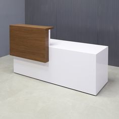 a white reception table with a wooden counter top in front of a gray wall and floor