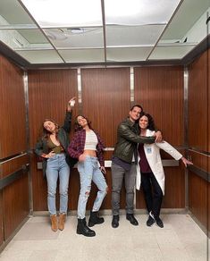 three people standing in an elevator with their arms around each other and posing for the camera