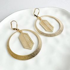 Add a modern touch to your style with this pair. Featuring sleek chevron pendants, these earrings are chic and versatile.  · Signature brushed gold plating on brass · Leverback clasp · 2.5" drop Geometric Earrings