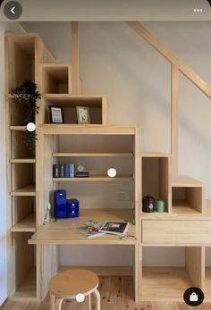 a wooden desk sitting under a stair case next to a wall mounted shelf with books on it