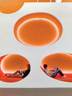 two people sitting on the floor with laptops in front of an orange circular design