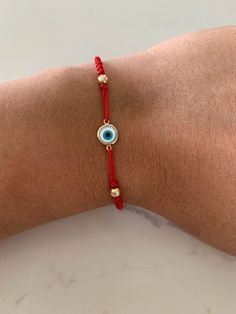 This 14K Solid Gold Evil Eye Bracelet is adorned by a luxurious 7MM Mother of Pearl design. Stretchable and handmade, it makes a perfect gift for any occasion. It is Unisex ♦ Materials: Evil Eye is 14K Gold, Mother Pearl, 4 Beads Beads are Gold-filled   ♦ Available colors: Gold and Blue  ♦ Eye measurements: 7 MM PRODUCTION TIMES Order processing time varies between 1-4 business days, we work on our pieces daily All orders placed on Sunday, or on a national holiday will begin processing the follo Red Round Beads Bracelet As Gift, Elegant Red Beaded Friendship Bracelets, Red Jubilee Bracelet Jewelry Gift, Gold Braided Bracelet With Evil Eye For Gift, Gold Braided Bracelet With Evil Eye As Gift, Gold Braided Evil Eye Bracelet As A Gift, Handmade Red Evil Eye Bracelet As A Gift, Adjustable Red Evil Eye Jewelry, Handmade Red Evil Eye Bracelet For Gift