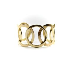 This is part of Chairish’s Fine Jewelry assortment.  Reminiscent of the Olympic rings, this fabulous cuff bracelet consists of a centre circle mirrored by circles layered on each side. Circa the 1970’s, this modernist bracelet uses negative space to create a bold presence on the wrist, while still having a light, open, airy feel. The sculptural nature of the piece makes it feel like a work of art. Sophisticated and playful, the olympian design makes this the champion of bracelets!   The bracelet Modern Round Metal Cuff Bracelet, Modern Metal Round Cuff Bracelet, Handmade Adjustable Modernist Cuff Bracelet, Gold Modernist Cuff Bracelet For Formal Occasions, Adjustable Modernist Cuff Bracelet With Polished Finish, Modernist Cuff Bracelet With Polished Finish, Modernist Bracelet, Modernist Polished Cuff Bracelet, Olympic Rings