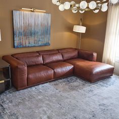 a living room with a large brown leather couch in front of a painting on the wall