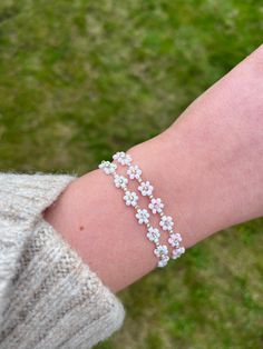 Handmade Beaded Flower Bracelet with gold colour findings. Adjustable daisy bracelet available in two variations: -White -Pink Please select your chosen colour from the menu when placing your order. Bracelet fits sizes between 16-19cm with use of extender chain. Please note some threads may be visible as this is a handmade product. Ensure to keep this piece out of water and avoid contact with fragrances and lotions as this can make the colours fade. Please drop me a message if you have any special requests regarding colouring and sizing and I will do my best to accommodate these! Bracelets are carefully presented on card display to ensure that they arrive in perfect condition. Delicate White Bracelets For Spring, White Delicate Bracelet For Spring, Delicate White Bracelet For Spring, Delicate White Flower Beaded Bracelets, Delicate White Flower Shaped Beaded Bracelets, Delicate White Flower Bracelets, White Wedding Bracelets For Spring, White Flower Friendship Bracelets For Spring, Delicate Flower Charm Bracelet For Spring