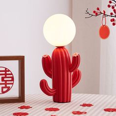 a red cactus lamp sitting on top of a table next to a wooden frame with chinese characters