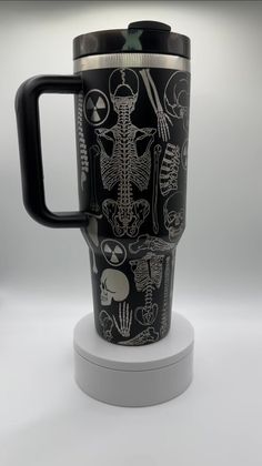 a black and white coffee cup with skeleton images on the front is sitting on a stand