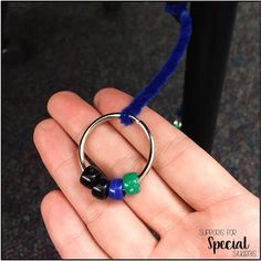 a person holding a ring with beads on it and a blue cord in the middle