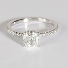 an engagement ring with a cushion cut diamond and pave set diamonds around the band