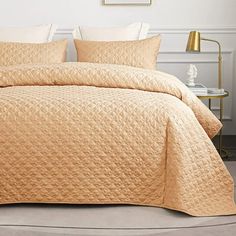 a bed with a yellow quilted comforter and two pillow cases on top of it