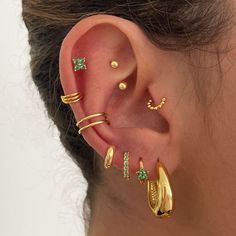 a close up of a person with ear piercings and gold jewelry on their ears