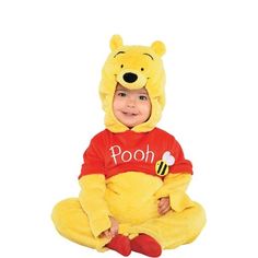 a little boy dressed in winnie the pooh costume sitting on the floor with his legs crossed