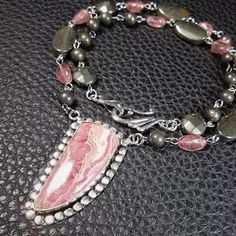 a close up of a beaded bracelet with beads and charms on a black surface