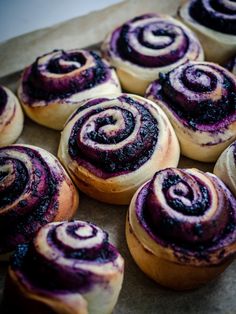 there are many different types of pastries on the table together, including blueberry rolls