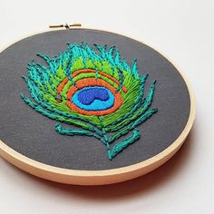 an embroidered peacock feather on a gray background