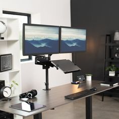 two computer monitors sitting on top of a wooden desk