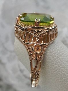 Natural Green Peridot 10k or 14k Rose Gold RingLovely Rectangle Design#D148 Make heads turn and stand out with this gorgeous piece of jewelry! This Edwardian reproduction filigree ring is made from rose gold and features an emerald cut high quality natural green Peridot gemstone measuring 9mm by 7mm. From the beautiful intricate floral daisy design to the inside of the band marked 10K or 14K for gold – this ring will take your look to the next level! Look no further than this exquisite vintage-i Emerald Cut Peridot Jewelry For Formal Occasions, Emerald Cut Peridot Jewelry For Formal Events, Vintage Gold Jewelry With Peridot, Vintage Gold Peridot Jewelry, 14k Rose Gold Emerald Cut Gold Ring, Formal Emerald Cut Peridot Jewelry, Emerald Cut 14k Rose Gold Ring, Yellow Gold Peridot Jewelry With Emerald Cut, Elegant Rectangular Peridot Rings