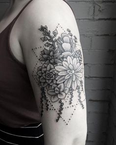 a black and white photo of a woman's arm with flowers tattooed on it