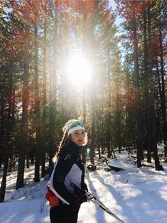 a woman is standing in the snow with skis on her head and poles up